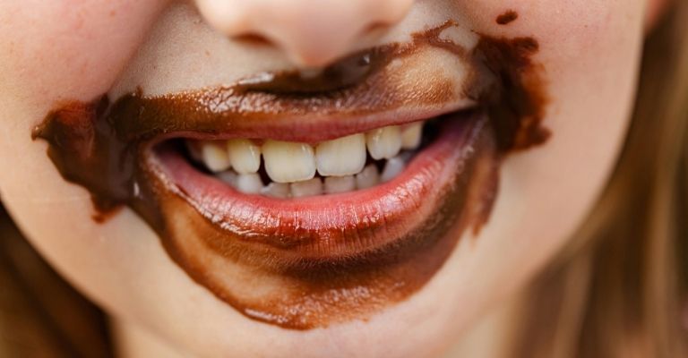 petite fille qui sourit avec du chocolat autour de la bouche